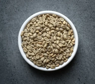 Bolivia FTO Colonial Caranavi green coffee beans in a white bowl on a dark tabletop