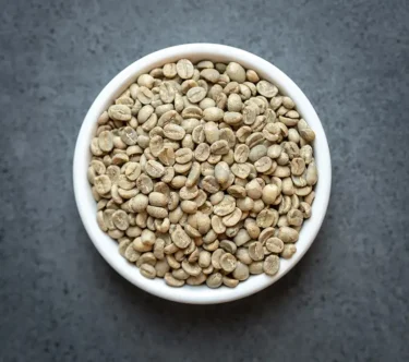 Bowl of Nicaragua Fair Trade Organic green coffee beans on a dark tabletop