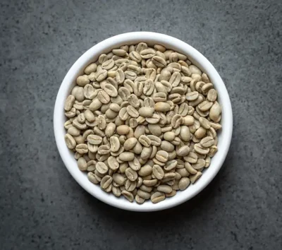 Bowl of Papua New Guinea NOP Enorga Organic green coffee beans on a dark stone background