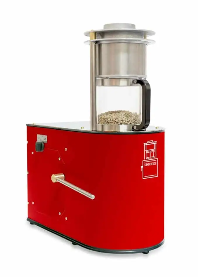 Red Sonofresco one-pound coffee roaster with a clear chamber containing unroasted green coffee beans.