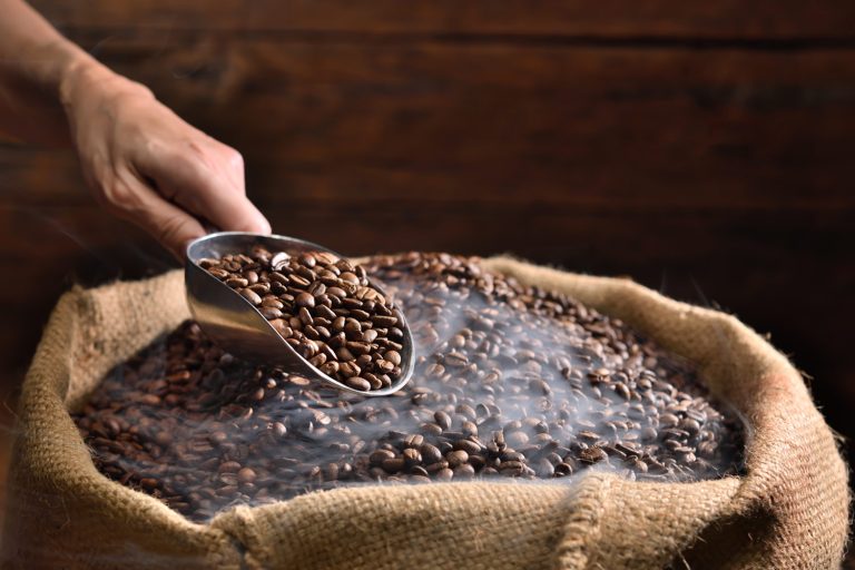 High-quality freshly roasted coffee beans, exuding rich aroma and deep brown color, ready to be ground and brewed for a delightful sensory experience.